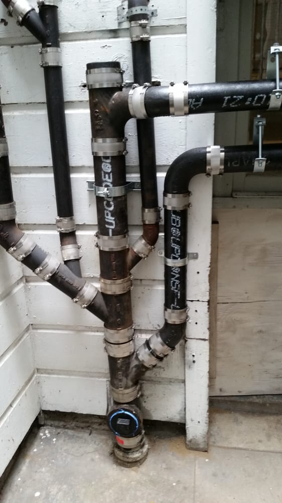 Newly installed exterior drain, waste and vent pipe system with labeled clean-outs and water meter connection